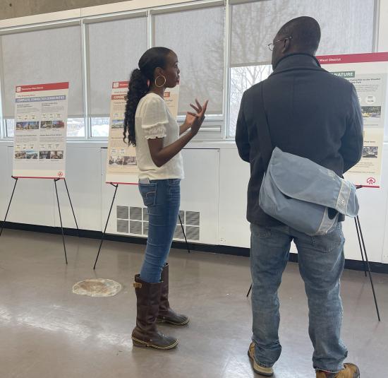 Two people standing looking at an information board during a public engagement meeting